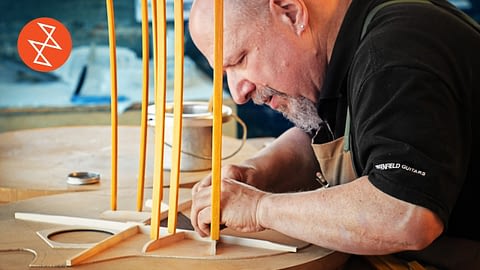 Old Man Carefully Building A Guitar